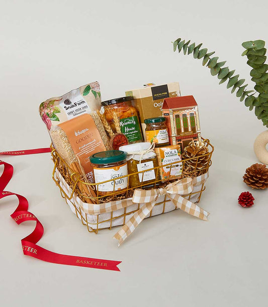 Rustic gold wire basket with gingham lining filled with gourmet jars, grains, and artisan condiments for New Year gifting