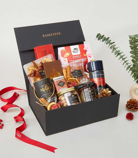Luxurious black gift box filled with gourmet treats, premium coffee, and artisan chocolates for New Year celebrations