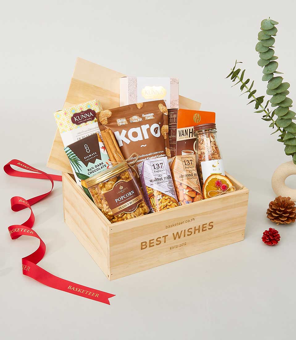 Wooden wellness gift box with gourmet nuts, plant-based milk, dark chocolate and popcorn butter for New Year