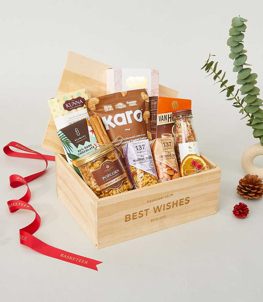 Wooden wellness gift box with gourmet nuts, plant-based milk, dark chocolate and popcorn butter for New Year