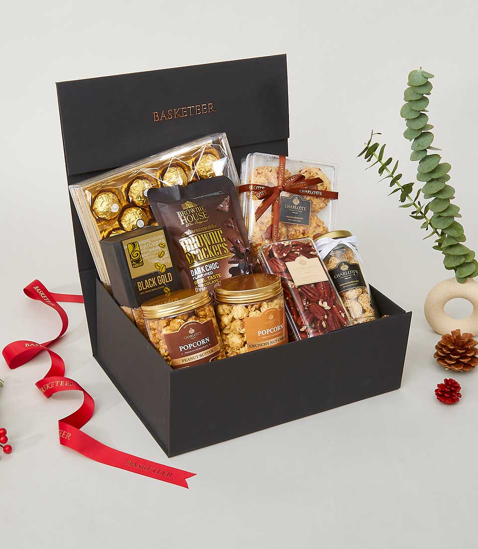 Luxurious black gift box with gold-embossed Basketeer branding, filled with gourmet chocolates, brownie crackers, popcorn,