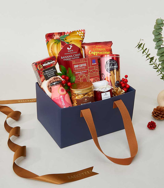 Navy blue gift box filled with Belgian chocolate, coffee, banana chips, and gourmet treats with festive red ribbon for New