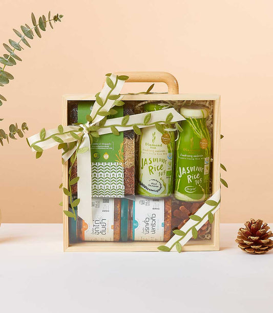 Wellness gift box with jasmine rice milk, chili paste, grains, and eucalyptus in wooden case with white ribbon