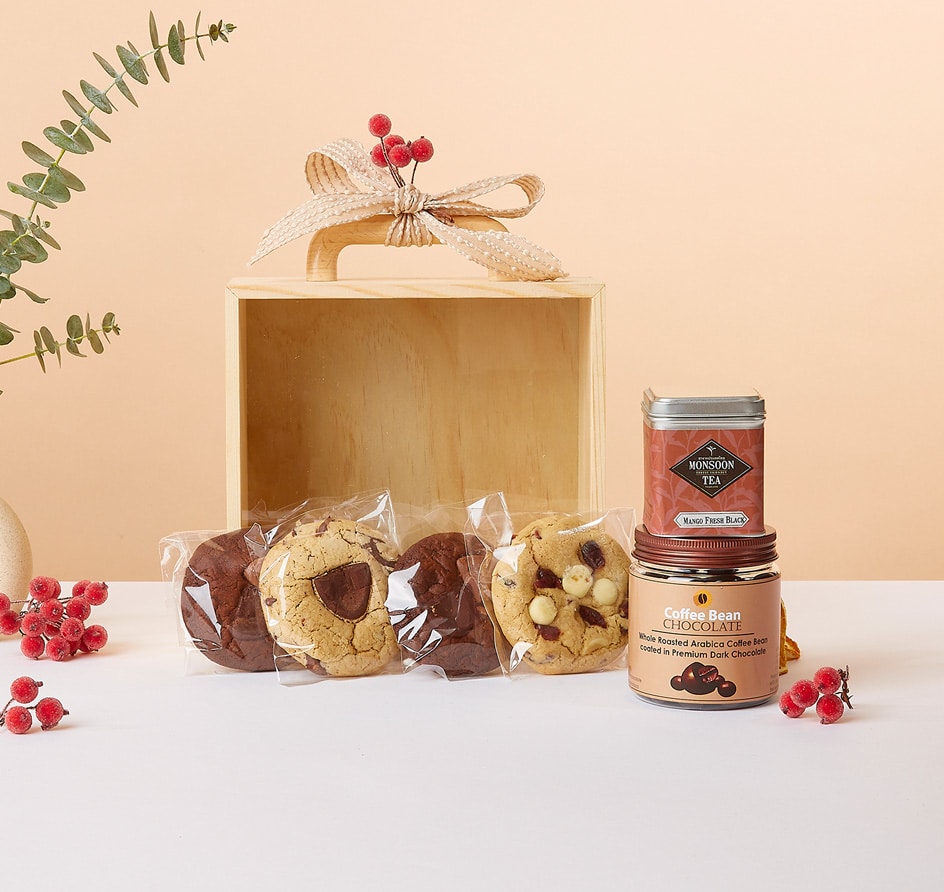 Gourmet wellness gift set with chocolate cookies, mango black tea, and coffee bean chocolates in wooden box with ribbon