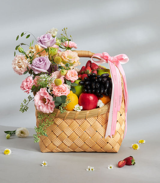 Woven wicker basket with pastel roses, carnations, fresh strawberries, grapes, and apples—birthday fruit and flower gift