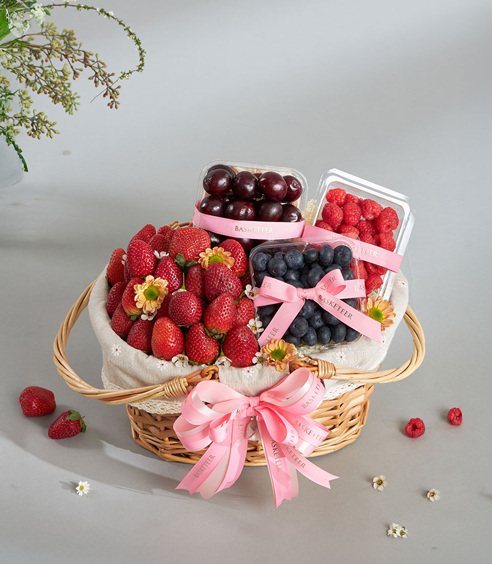 Premium fresh berry gift basket with strawberries, cherries, blueberries, and raspberries in wicker with pink ribbon