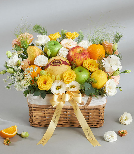 Premium wicker fruit and flower basket with yellow roses, fresh apples, oranges, and pears tied with gold ribbon