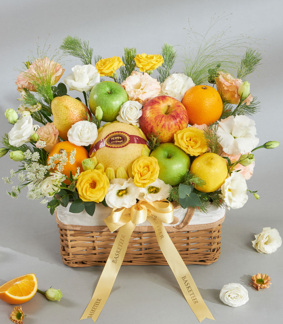 Premium yellow-tone fruit and floral gift basket with fresh apples, oranges, pears, white and yellow roses, and eustoma