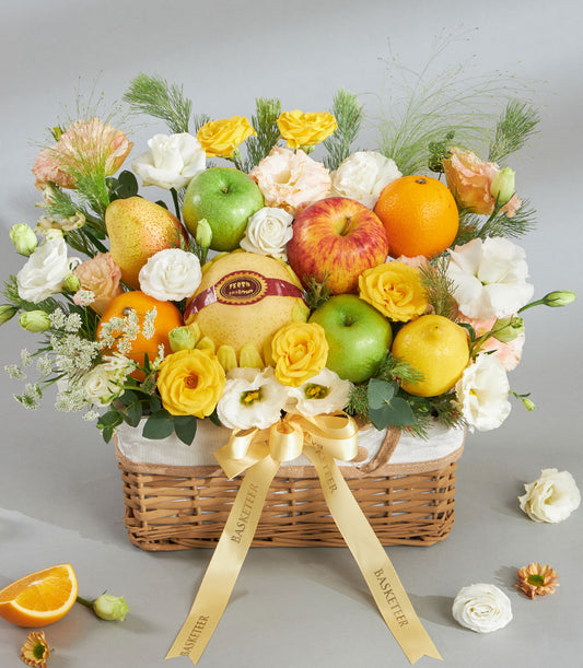Premium yellow-tone fruit and floral gift basket with fresh apples, oranges, pears, white and yellow roses, and eustoma