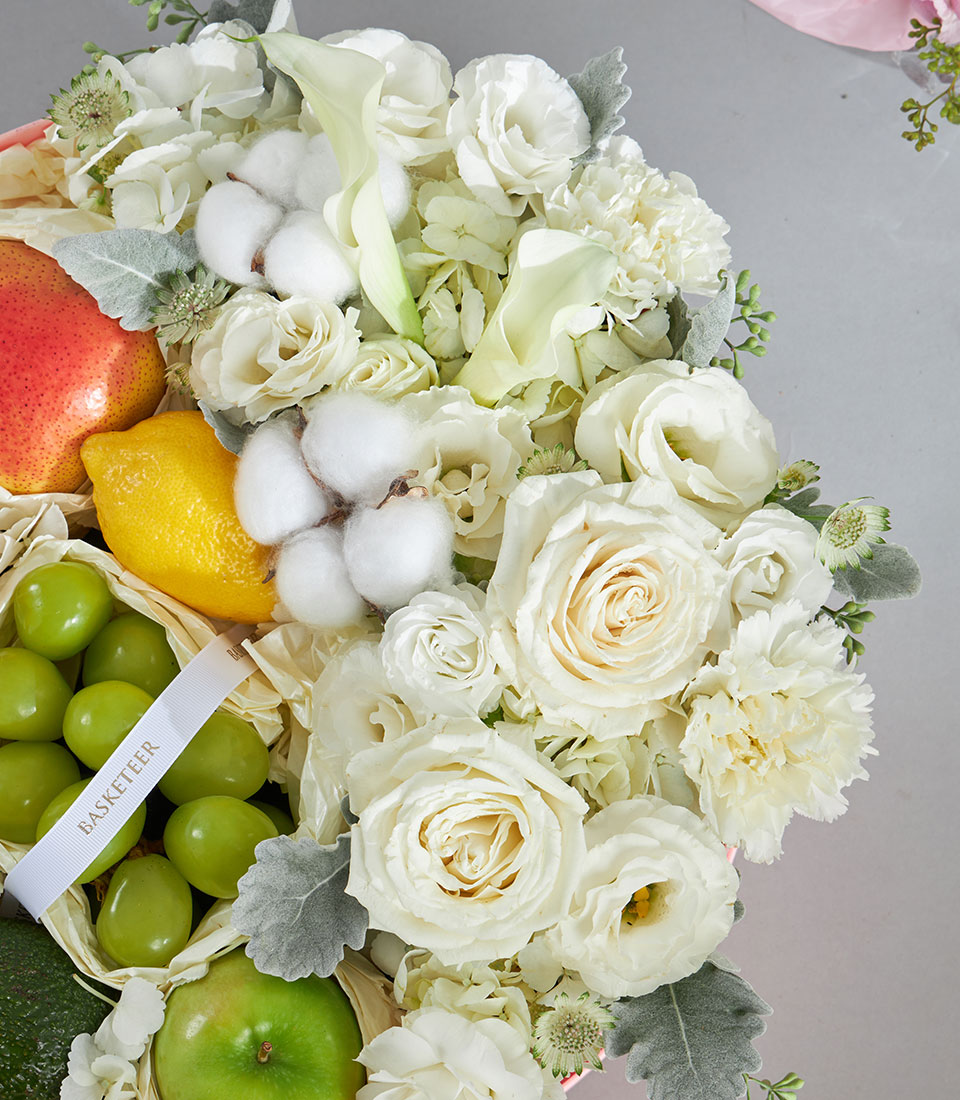 Elegant round luxury gift box with fresh fruit, white roses, calla lilies, and delicate florals