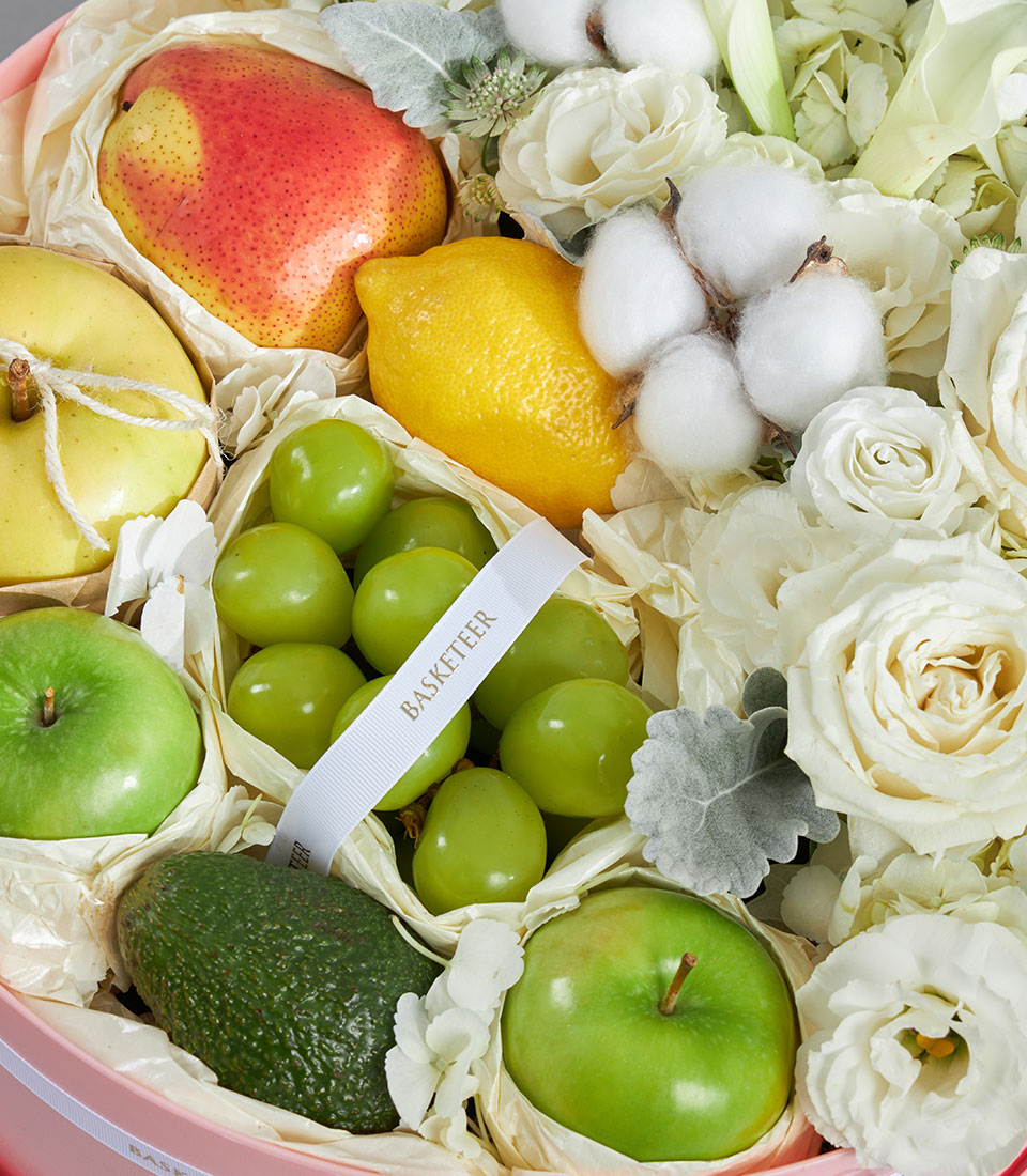 Luxury fruit and white floral round box with fresh pears, apples, grapes, and premium roses in blush pink container