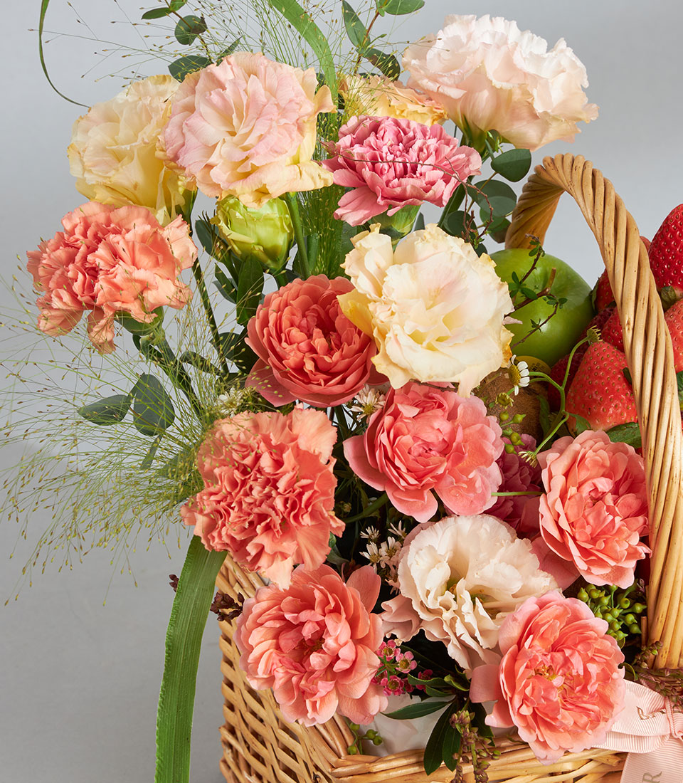 Peach and coral garden roses with strawberries in woven wicker gift basket