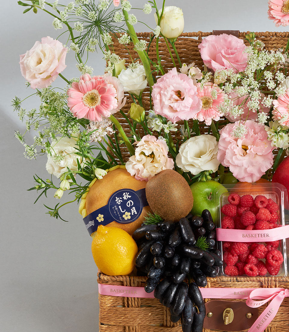 Premium wicker basket with pink roses, gerberas, eustoma, fresh lemons, kiwis, apples, grapes and raspberries
