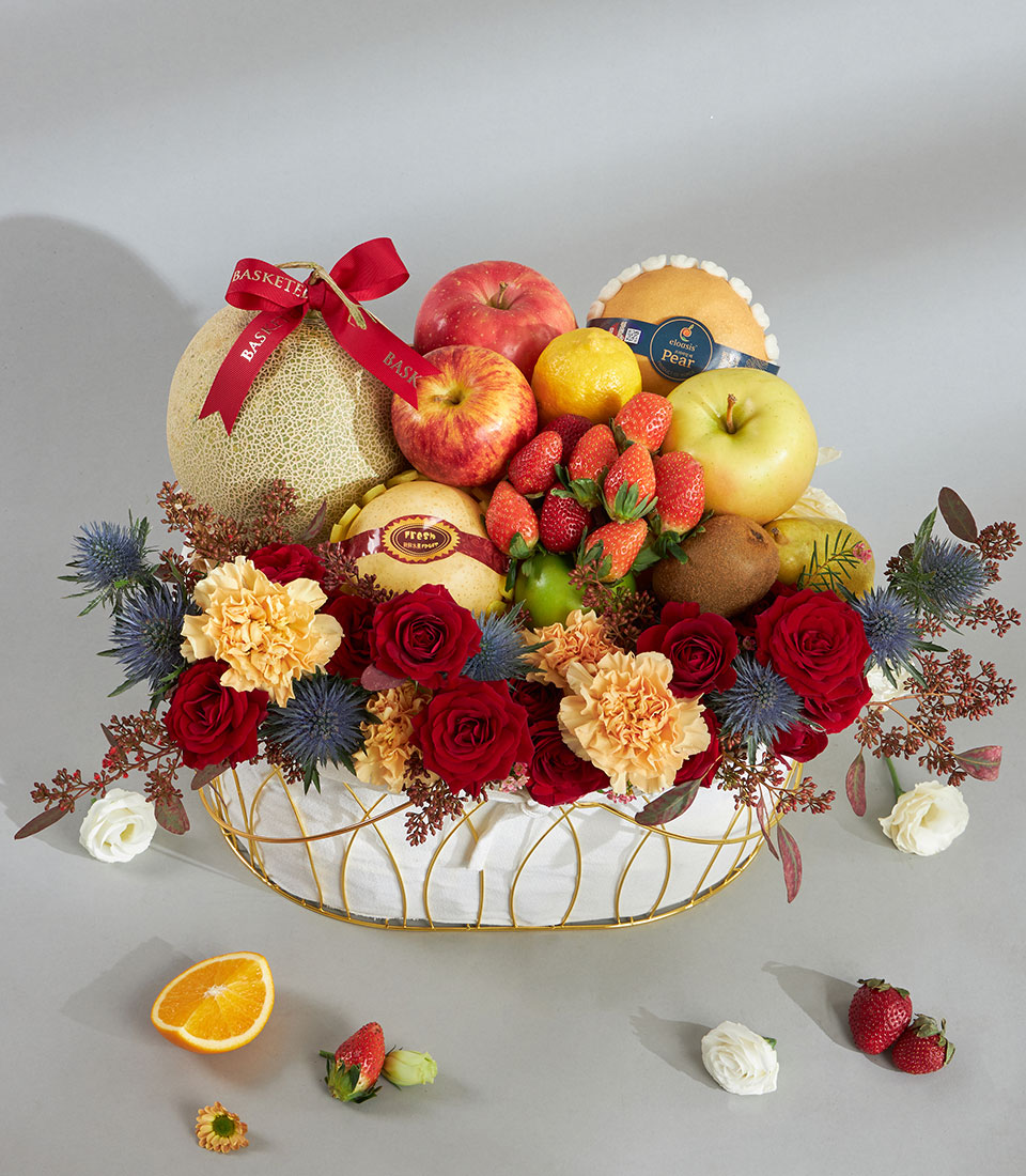 Luxury red and gold fruit basket with fresh tropical fruits, deep red roses, and carnations