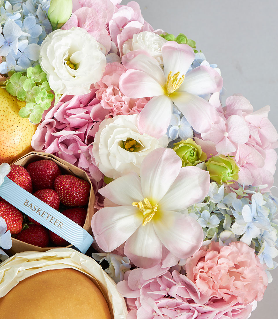 Soft pastel premium fruit and floral round box with white tulips, hydrangeas, fresh pear and strawberries for birthday