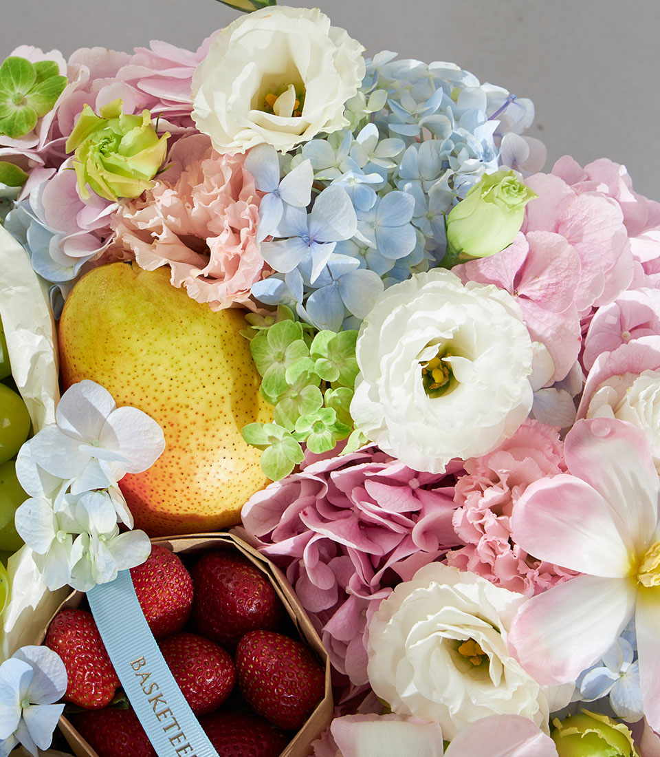 Soft pastel round gift box with fresh pear, strawberries, white eustoma, pink hydrangeas, and carnations for birthday
