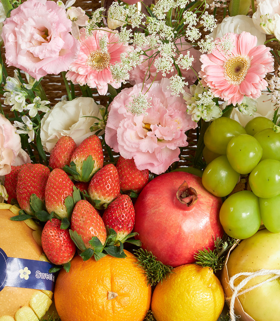 Premium pink pastel fruit and floral gift basket with roses, strawberries, pomegranate, and seasonal citrus