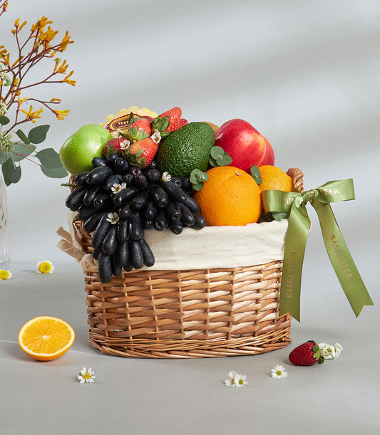 Premium wicker fruit basket with Moon Drop grapes, strawberries, apples, and imported selection, cream ribbon detail