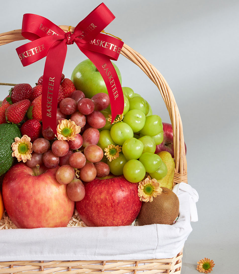 Premium mixed imported fruit basket with red apples, grapes, strawberries, and fresh seasonal fruit in woven wicker