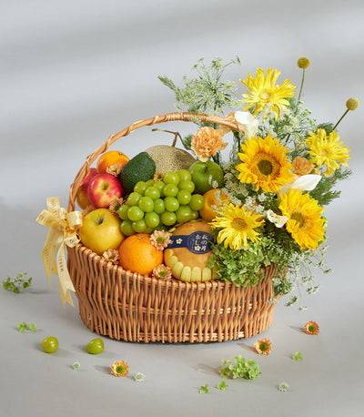 Bright yellow fruit and floral gift basket with fresh apples, grapes, citrus, sunflowers and calla lilies