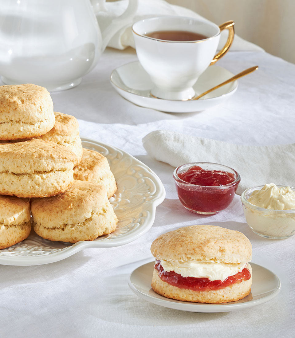 Freshly baked British scones with clotted cream, strawberry jam, and traditional tea service