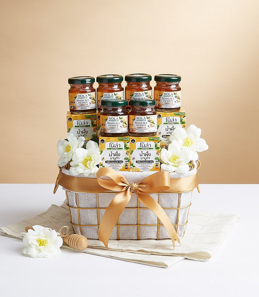 Nola Superfood gift basket with raw honey jars, golden ribbon, and artisan wellness gifting