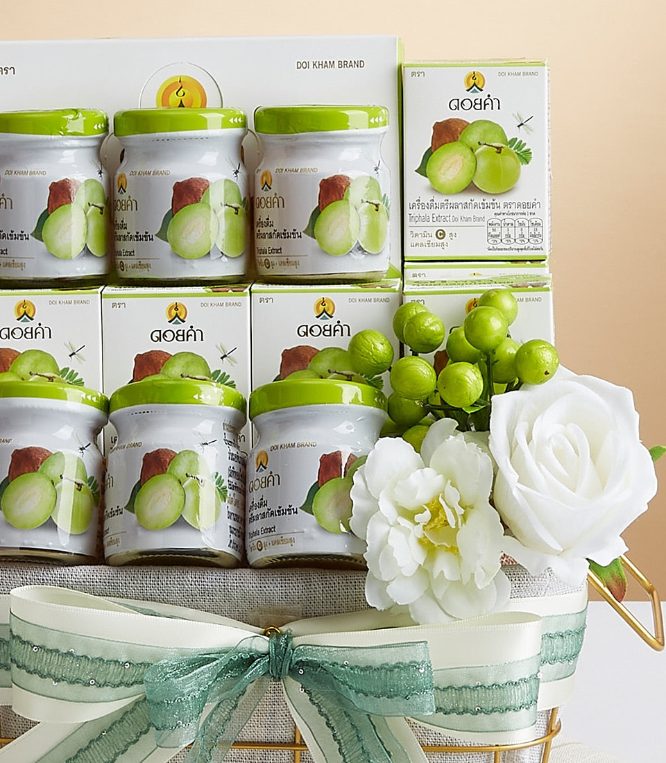 Premium Doi Kham Triphala Extract wellness gift basket with green-lidded glass jars, cream ribbon bow, and white flowers