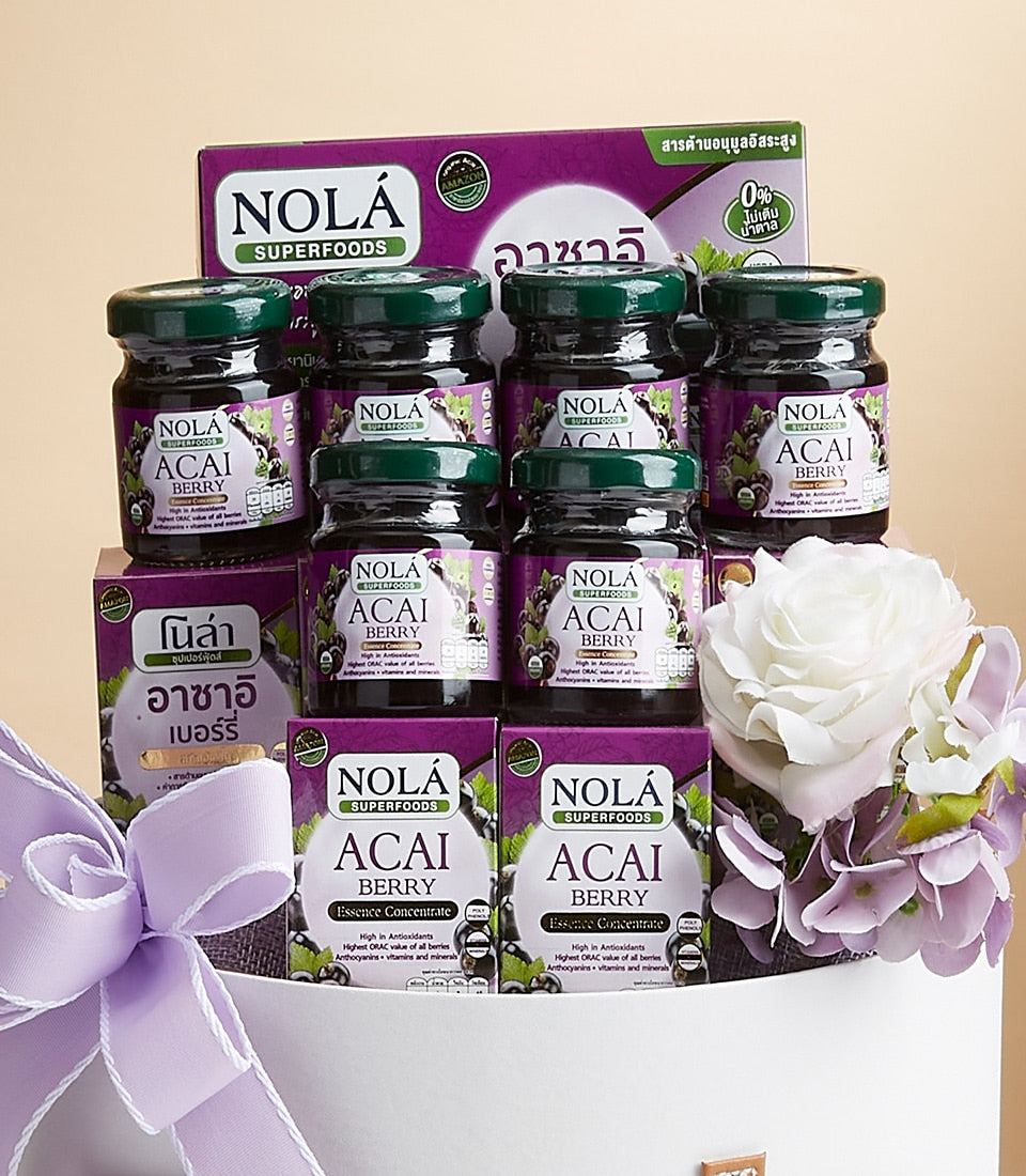 Nola Acai Berry superfood gift set with glass jars, essence concentrate boxes, and purple ribbon in white basket