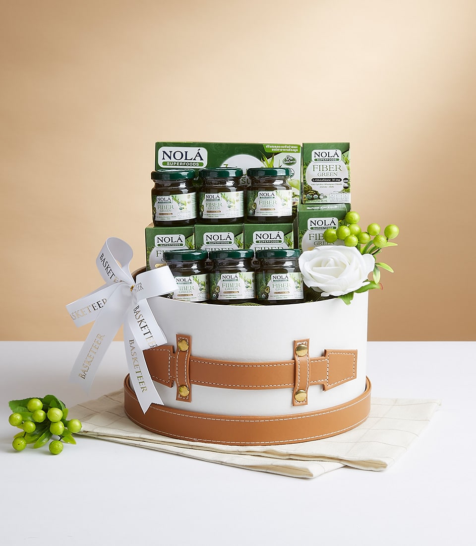 Nola Fiber Green wellness gift basket with white cylindrical box, tan leather strap, and green superfood jars