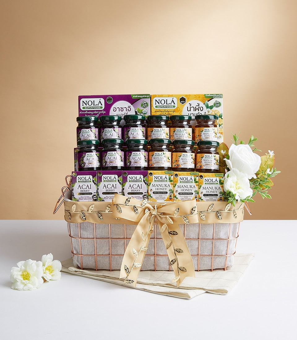 Rose gold wire mesh gift basket with Nola Superfoods acai berry and manuka honey jars, gold ribbon bow, white flowers