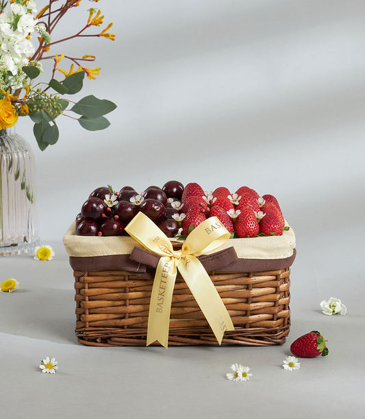 Premium cherry and strawberry gift basket with golden ribbon bow and white flower accents