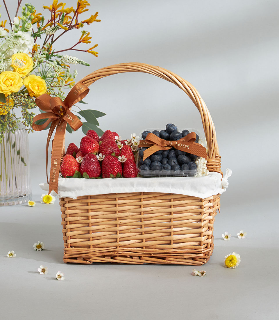 Premium strawberry and blueberry gift basket with fresh roses and wildflowers in wicker