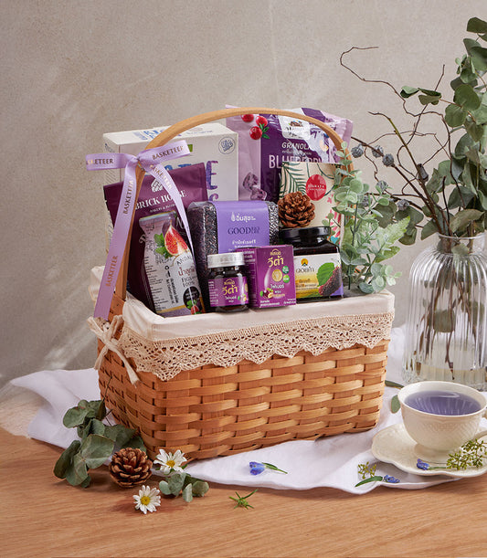 Purple wellness gift basket with blueberry granola, superfood rice, fig juice, and health supplements in woven wood hamper