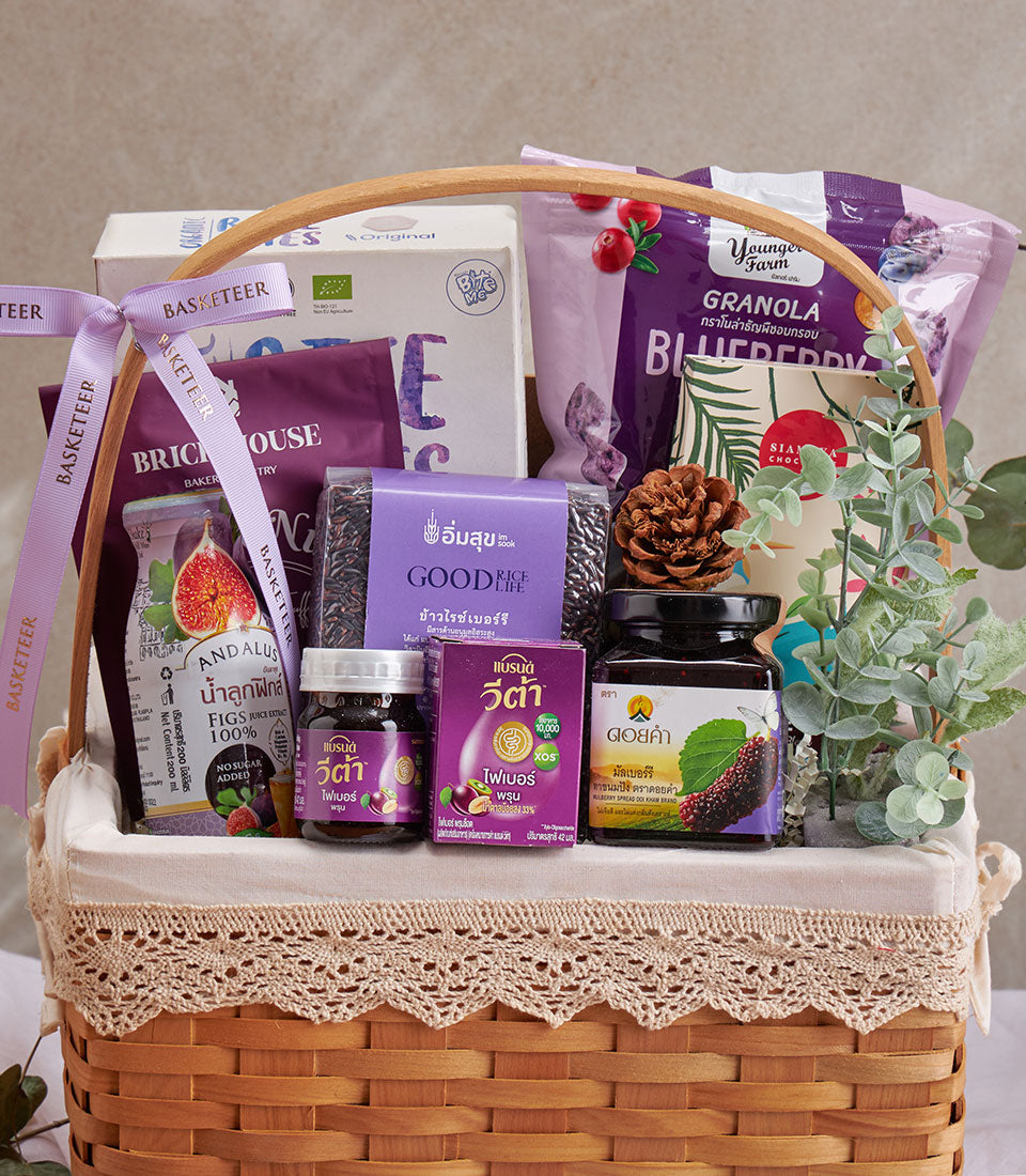 Woven wicker wellness gift basket with blueberries, superfoods, and health supplements, tied with purple Basketeer ribbon