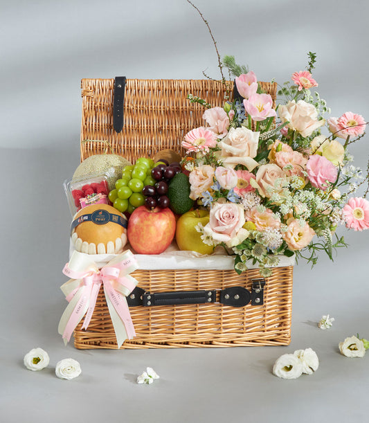 Premium wicker basket with fresh Shine Muscat grapes, tropical fruit, and pink rose floral arrangement for gifting