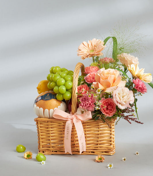 Peach and pink floral fruit gift basket with fresh grapes, pear, and roses for birthday celebrations