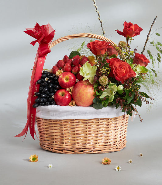 Basketeer premium hamper delivery Thailand: Wicker basket overflowing with red roses, apples, grapes and strawberries. Finished with a red ribbon, a luxurious gift.
