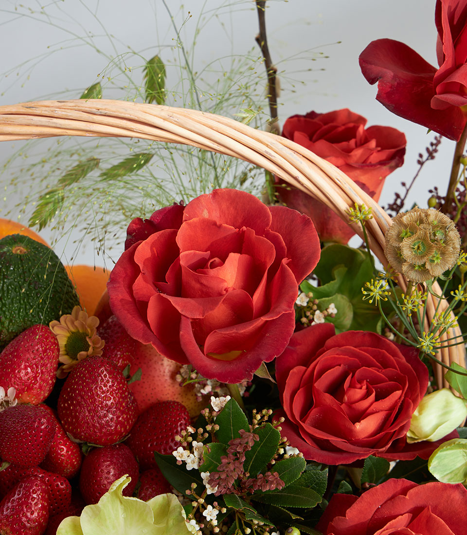Basketeer premium hamper overflowing with strawberries and oranges, accented with lush red roses in a classic wicker basket. Perfect fruit & floral gift Bangkok.