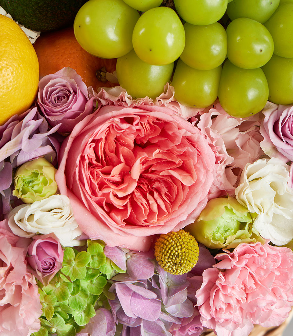 Pastel premium fruit and floral basket with coral garden roses, pink roses, hydrangeas, fresh citrus and grapes