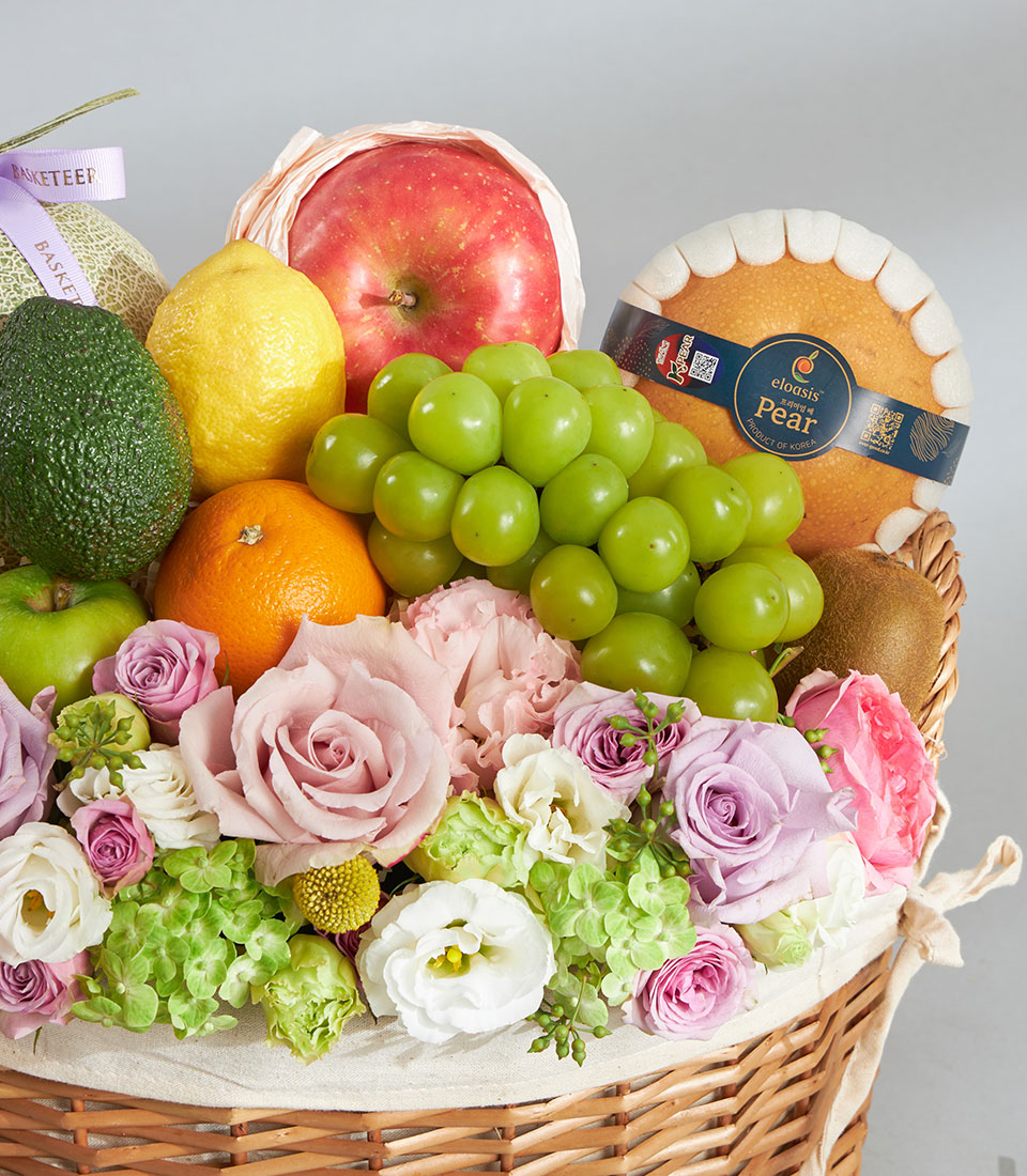 Pastel fruit and floral birthday basket with fresh roses, apples, grapes, and seasonal produce in woven wicker