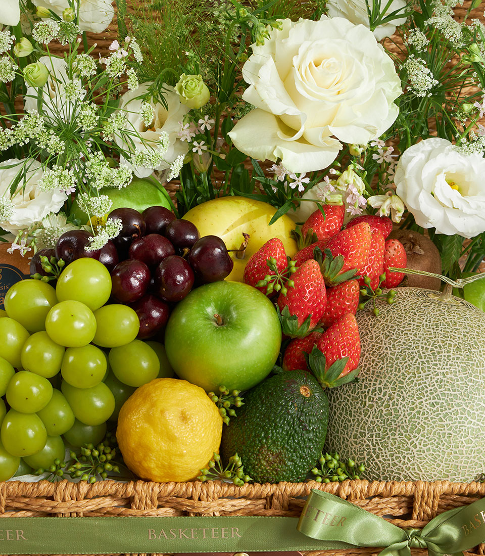 Elegant white roses and fresh fruit in a woven basket with green ribbon bow, premium gift hamper