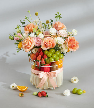 Pastel floral and fresh fruit gift basket with strawberries, grapes, and oranges for birthday celebrations