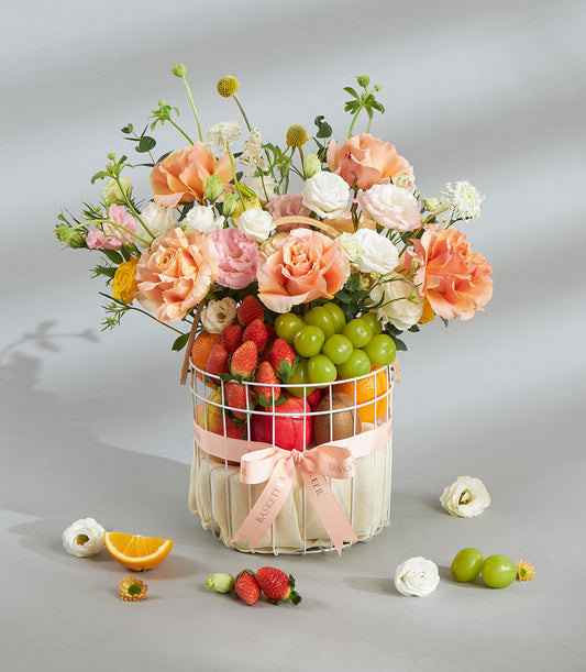 Pastel floral and fresh fruit gift basket with strawberries, grapes, and oranges for birthday celebrations