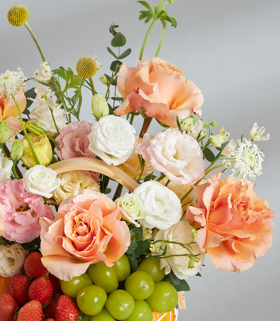 Premium fruit and pastel floral birthday basket with peach roses, strawberries, and green grapes