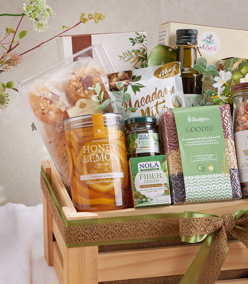 Organic wellness gift hamper with pad thai, macadamia nuts, honey lemon syrup, and olive oil in wooden crate with green