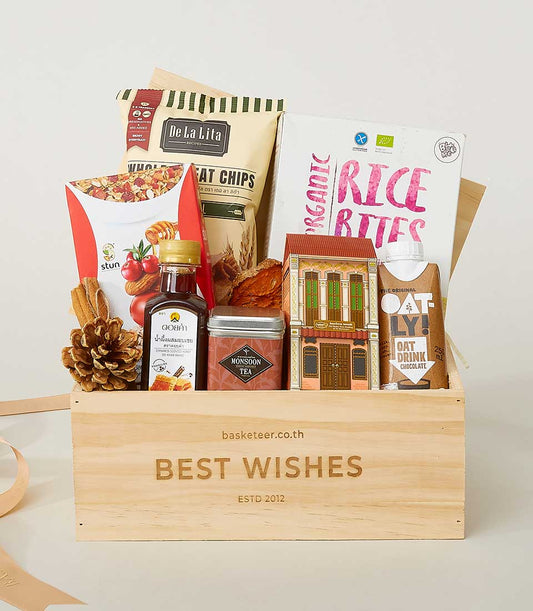 Wooden gift box filled with gourmet snacks, tea, honey and chocolate oat drink for New Year wishes