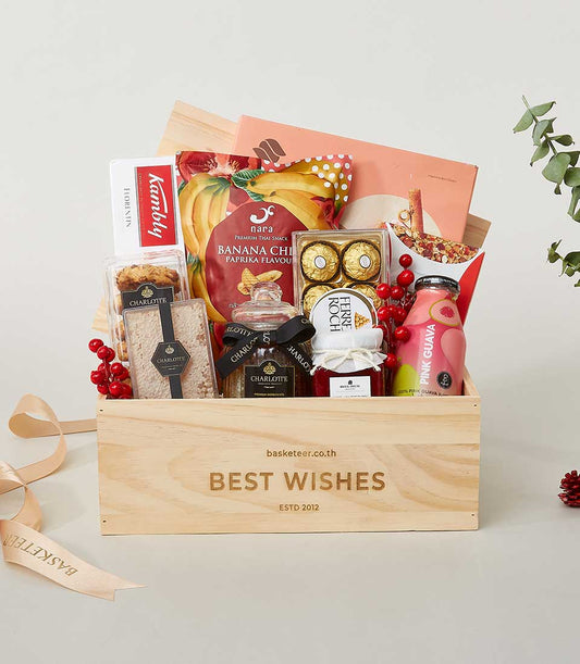 Wooden gift box engraved "Best Wishes" filled with gourmet snacks, chocolates, and pink guava juice for New Year gifting