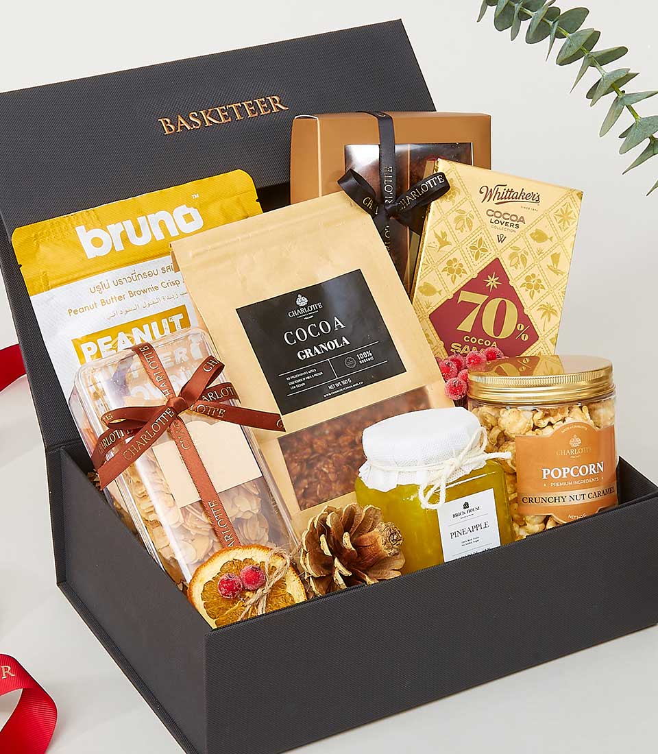 Luxurious black gift box filled with gourmet chocolates, granola, brownie crisps, jam, and caramel popcorn for New Year
