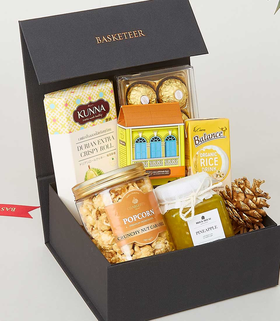 Luxury black gift box with gourmet food pairings including durian roll, chocolates, popcorn, and pineapple preserve for New
