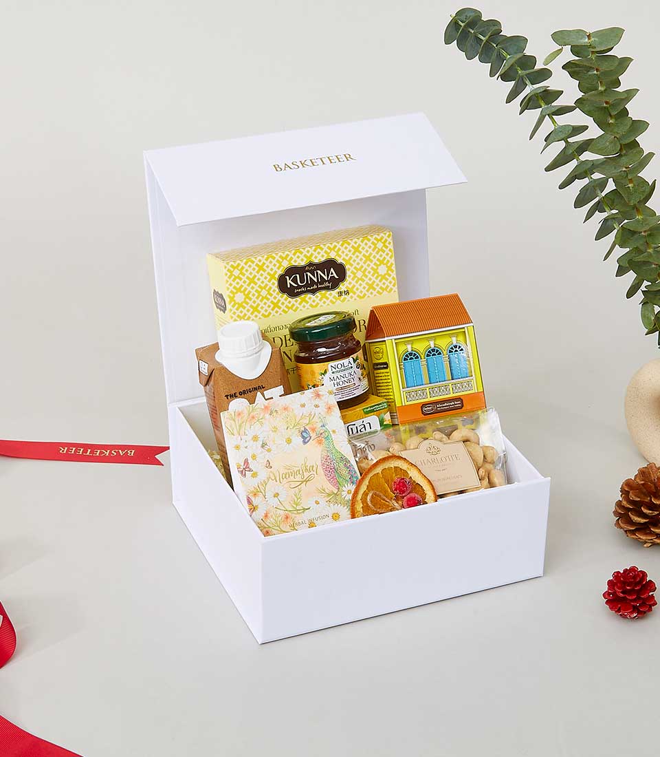 White luxury gift box filled with gourmet treats, honey, cashews, and artisan goods for New Year celebrations
